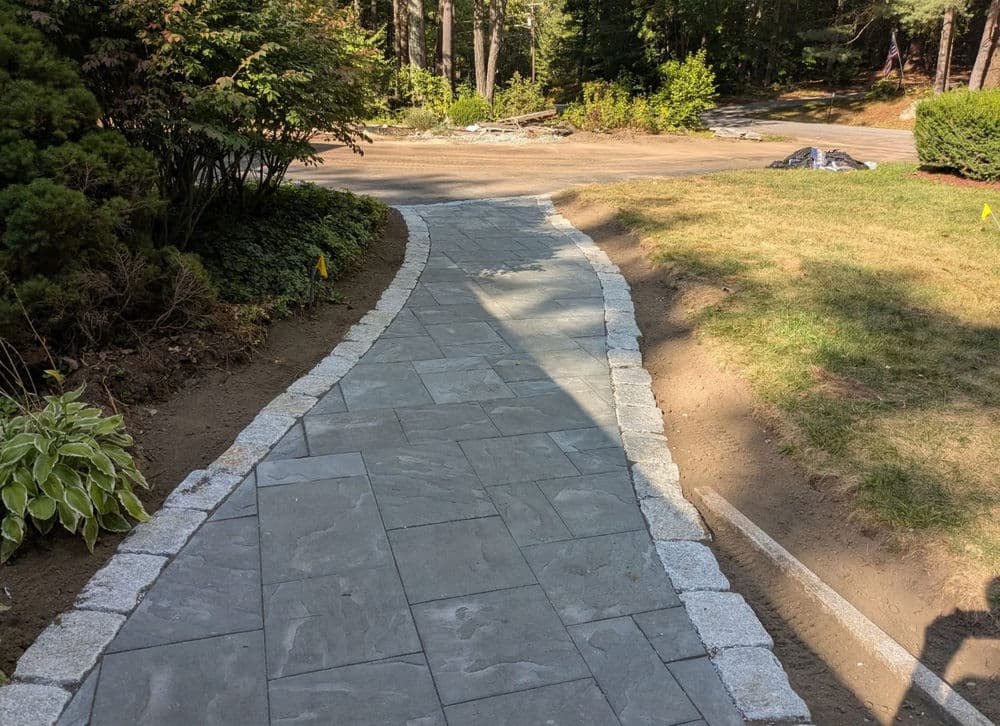 Curved stone pathway with granite edges in a landscaped garden setting.