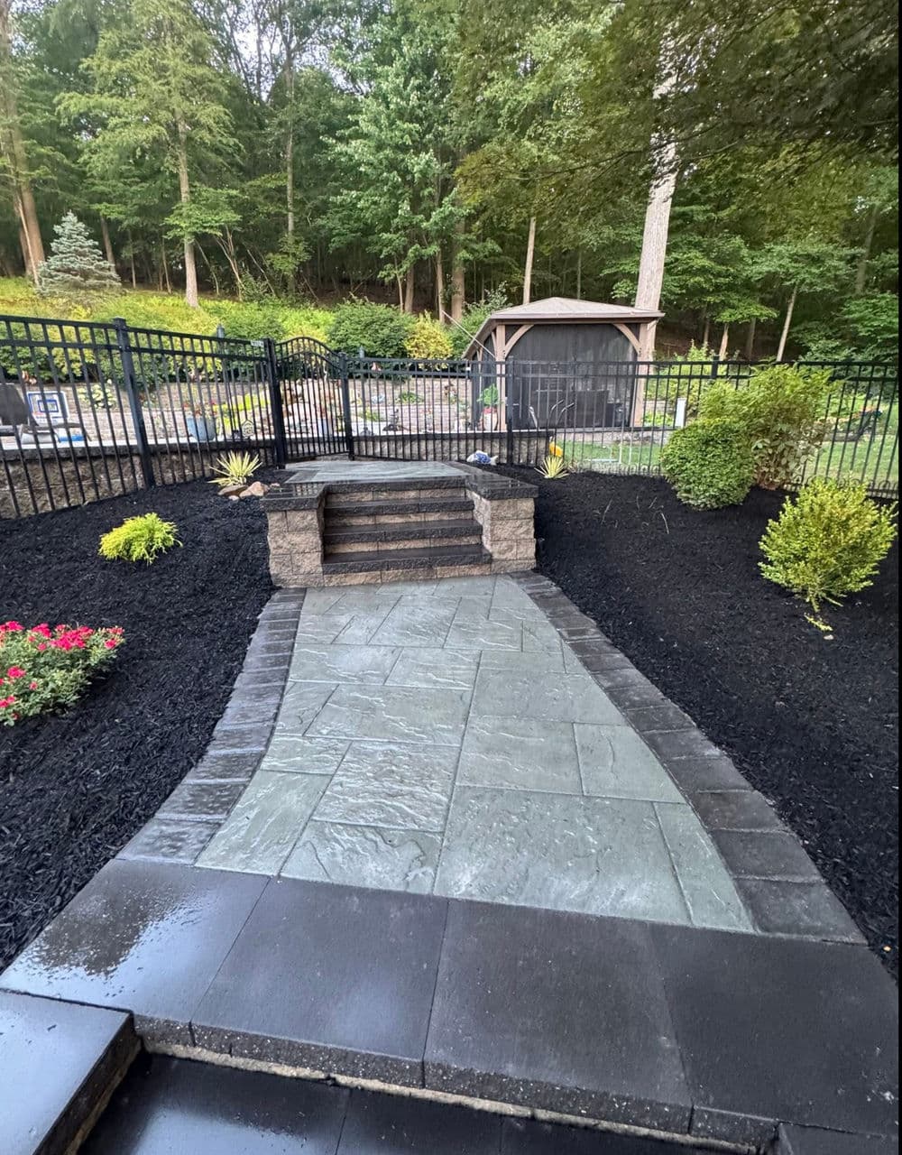 Stylish outdoor pathway with stone steps, landscaped garden, and fenced area.
